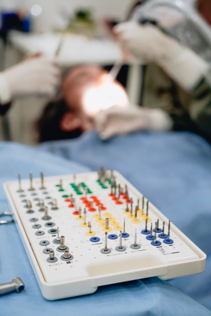 journey Close-up of a dental implant kit with dentist working on a patient in the background.
