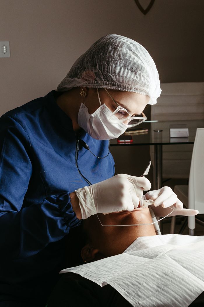 team-04 A dentist in a medical clinic performing a procedure on a patient, focusing on dental care and hygiene.