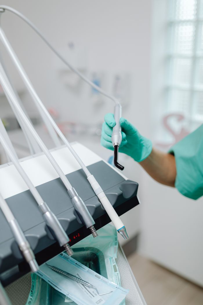 services-03 Close-up of dental tools in use with a gloved hand at a dental clinic, showcasing modern dentistry.