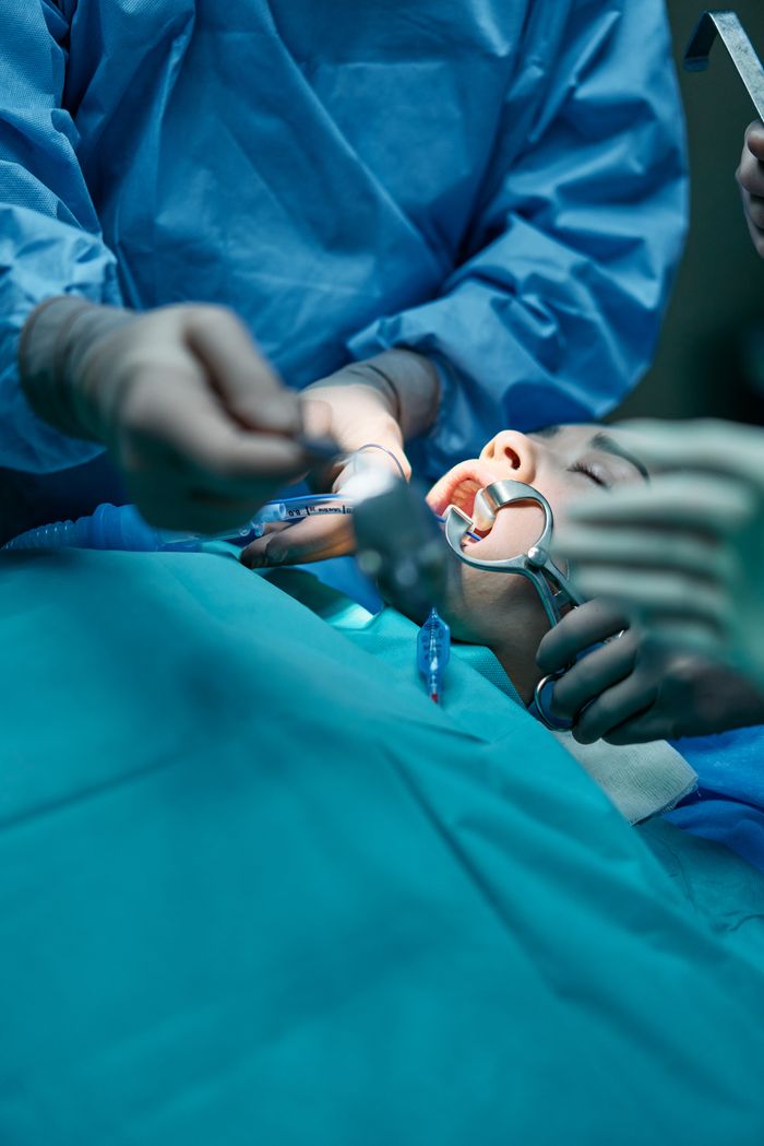 team-02 Close-up of a surgical team conducting an oral procedure in a sterile hospital environment.